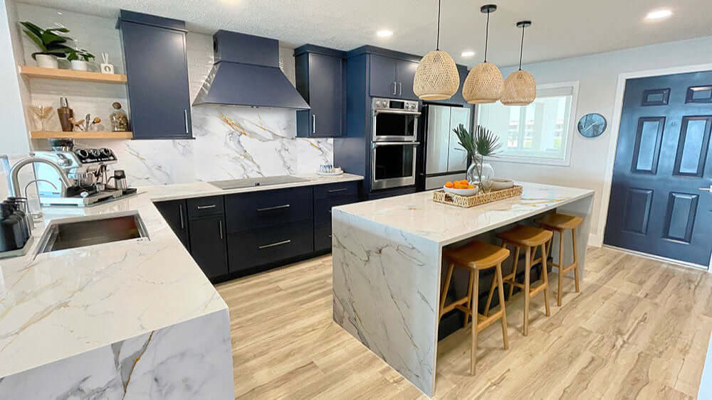 Modern kitchen with navy cabinets, marble countertops, wood accents, and a large island with bar stools
